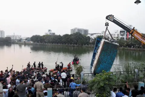 Reuters A crane pulls out the boat which capsized in Harni Lake carrying children and teachers who were on a picnic, in Vadodara, India, January 18, 2024.