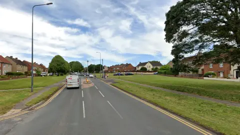 Google A wide view looking up Northcote Road with houses and trees either side