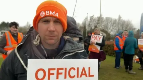 A man in a orange hat at a picket line