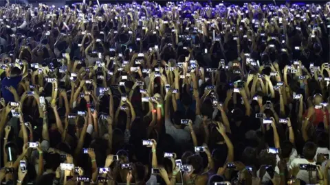 EPA Fans use their phones at concert