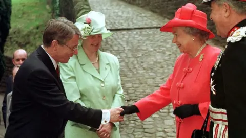 Getty Images First Secretary of the Assembly at the time, Alun Michael (L), accompanied by his wife Mary greets The Queen and the Lord Lieutenant of South Glamorgan Norman Lloyd Edwards at Llandaff Cathedral in Cardiff, Wales, 26 May 1999. The Queen is in Cardiff to open the National Assembly of Wales at Crickhowell House this afternoon.