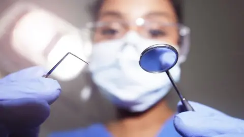 Getty Images Dentist looking into patient's mouth