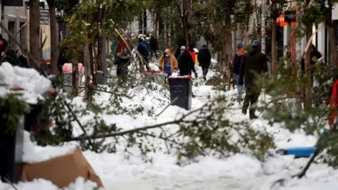 Reuters People walk through the snow and among fallen branches in Madrid, Spain January 10