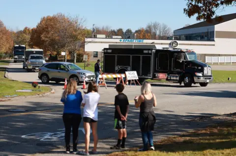 Getty Images Locals watch police leave the site of one of the shootings