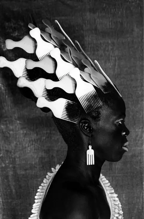 Zanele Muholi Person wearing afro combs in their hair and as earrings.