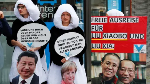 Reuters Protesters dressed as pandas with a big picture of Liu Xiaobo and Liu Xia, and slogans in German