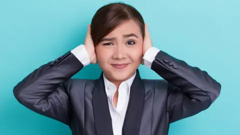 Getty Images Businesswoman covering her ears