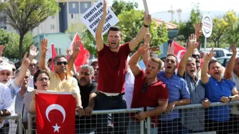 AFP People protest against arrested soldiers who allegedly participated in last year's attempted coup as they arrive for their trial (01 August 2017)