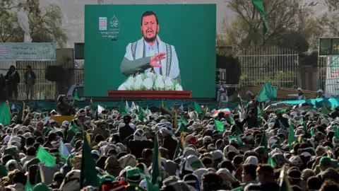 Reuters People watch as Houthi leader Abdul Malik al-Houthi delivers a speech on a TV screen during a rally marking the birthday of Prophet Muhammad in Sanaa, Yemen (29 October 2020)