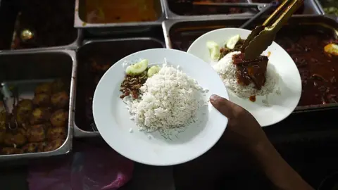 Empics In this picture taken 25 March 2015 a Malaysian stall assistant serves Nasi Lemak dish on a plate at the 'Nasi Lemak Tanglin' stall in Kuala Lumpur