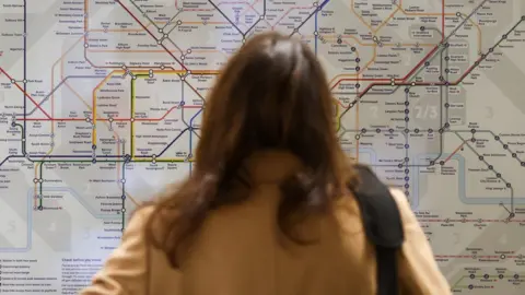 TOM NICHOLSON Woman looking at tube map