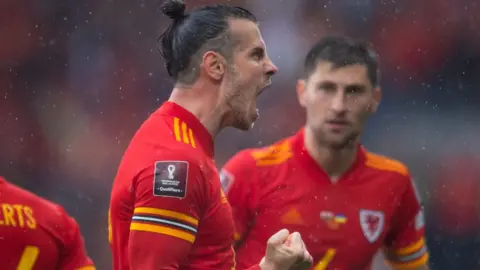 Getty Images Gareth Bale roars with Ben Davies behind him as Wales qualify for World Cup 2022 after beating Ukraine