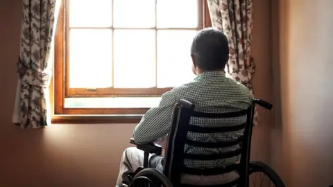 Getty Images Man in a wheelchair looking out of a window