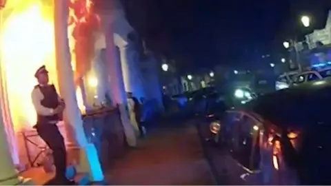 A police officer stood by a burning building