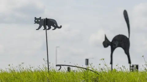 National Highways A small black cat sculpture by a larder black cat sculpture