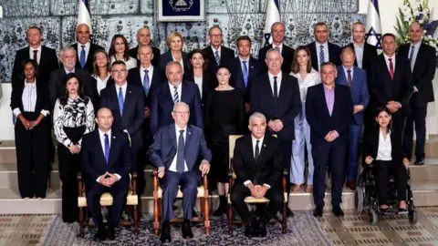 Reuters Israel"s President Reuven Rivlin (front row, centre) sits next to Prime Minister Naftali Bennett and ministers of the new Israeli government in Jerusalem (14 June 2021)