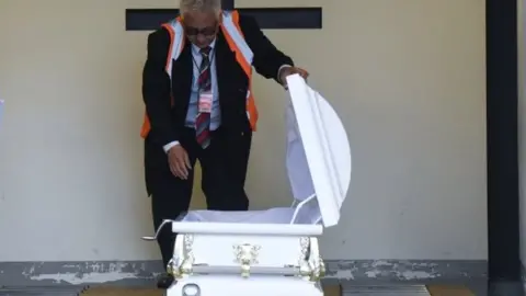 AFP/Getty Images An official looks at the coffin containing the body of Jakelin Caal in Guatemala City. Photo: 23 December 2018