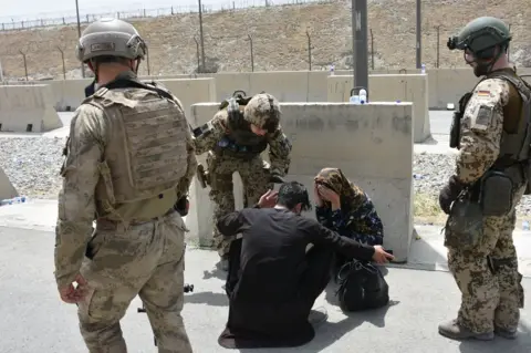 Anadolu A woman buries her head in her hands at Kabul airport as thousands tried to gain access to flights.