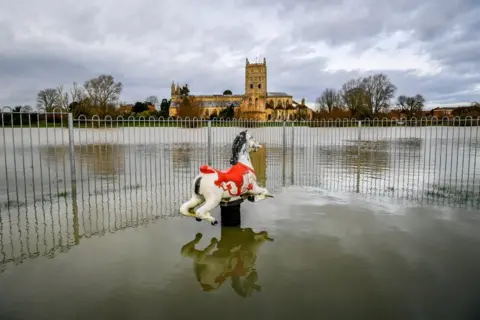 Ben Birchall/PA A rocking horse in a park is partially submerged in flood water around Tewkesbury Abbey, Gloucestershire, after storms and heavy rain across the UK. 16 January 2020