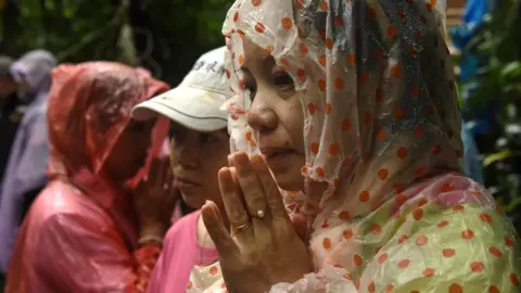 Getty Images A woman is pictured praying in waterproof hood outside of site