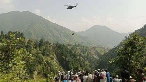 Getty Images A soldier slings down from a helicopter during a rescue mission to recover students stuck in a chairlift