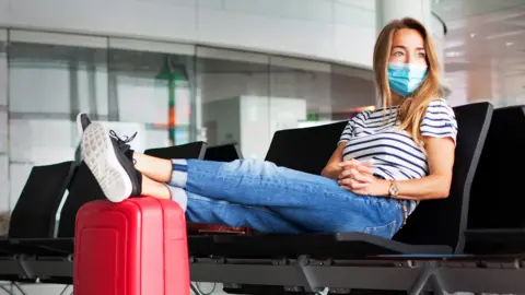 Getty Images Woman wearing a mask at an airport