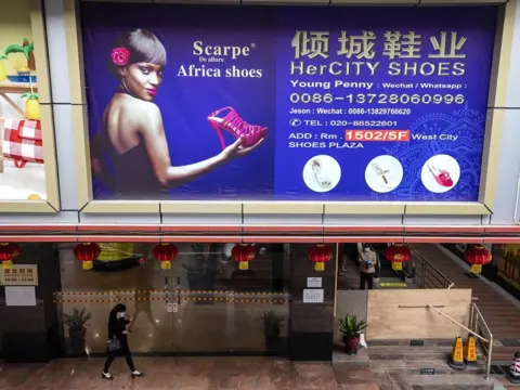 EPA A woman passes by billboard in part of the town where most of the African people lives and works in Guangzhou, Guangdong province, China, 13 April 2020.