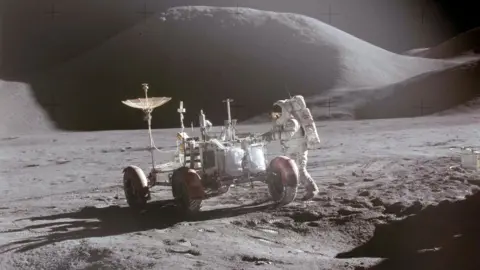 NASA Astronaut David Scott approaches the Lunar Roving Vehicle (LRV) during the Apollo 15 mission, July 1971