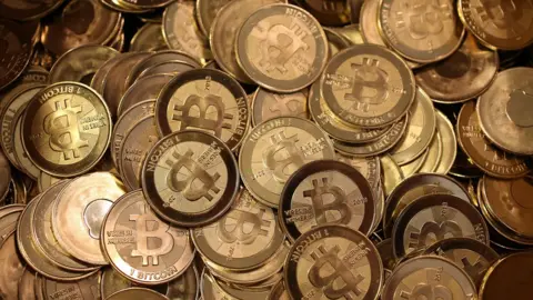 Getty Images A pile of bitcoin pieces sit in a box