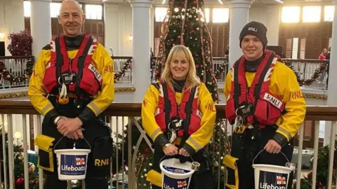 RNLI Sarah and two male RNLI colleagues collecting donations for the RNLI in a shopping centre