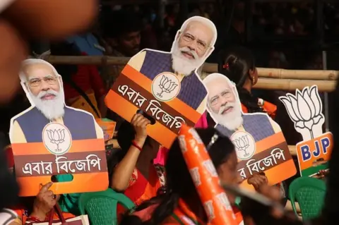 Getty Images Prime Minister Narendra Modi's fans and BJP supporters with cut outs and masks of Modi during his Election Campaign rally in support BJP candidate for West Bengal Assembly polls in Howrah, India on April 06, 2021.