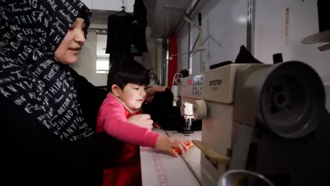 Kalbinur Tursan working in her tailor shop in 2019