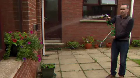 A man, Jim Balmer, watering his plants