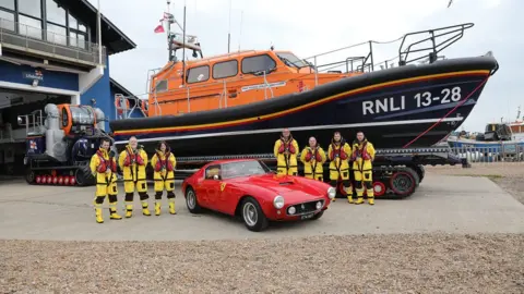 KTBruce/RNLI/PA The new lifeboat, called the Richard and Caroline Colton, and the lifeboats crew, with a 1960 red Ferrari 250 GT SWB which sold for £6.6m