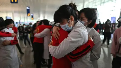 Getty Images Medical staff from Jilin Province (in red) hug nurses from Wuhan after the Covid-19 lockdown was lifted, 8 April 2020