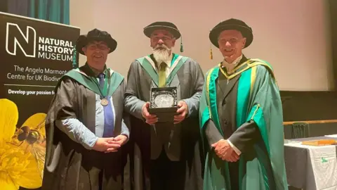 British Naturalists' Association Neil Garrick-Maidment (centre) receives the David Bellamy Award