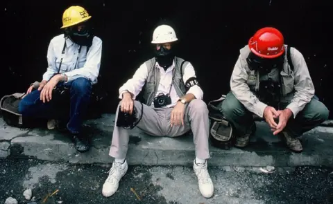 Kim Newton Charlie Cole sitting with two other men wearing gas masks and helmets