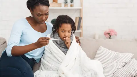 Getty Images Mother looking at child's thermometer reading