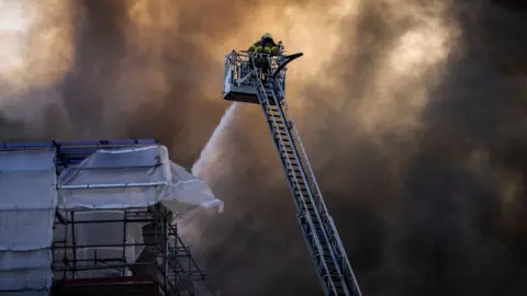 Getty Images A firefighter tries to extinguish flames at the historic Boersen Stock Exchange in Copenhagen on Tuesday, April 16, 2024