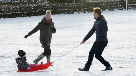 PA Media A family with a sledge