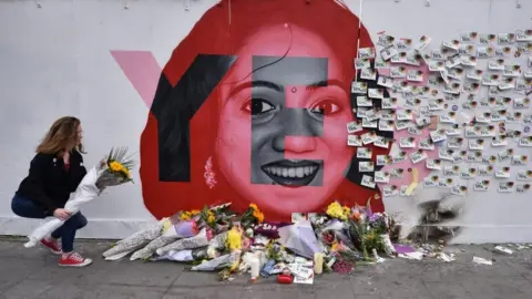 Getty Images A young woman leaves flowers at the Savita Halappanavar mural in Dublin