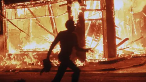 Getty Images A man runs past a burning building in Brixton