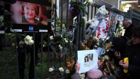 AFP/Getty Images People lay flowers in front of the apartment in Paris where Mireille Knoll lived. Photo: 28 March 2018