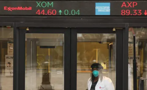 Getty Images Woman in mask in front of share price board