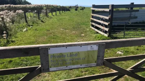 Sign on gate saying land beyond is private