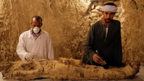 EPA Archaeologists work on a mummy at a tomb at Draa Abul Naga necropolis on Luxor’s west bank, 700km south of Cairo, Egypt, 09 December 2017.