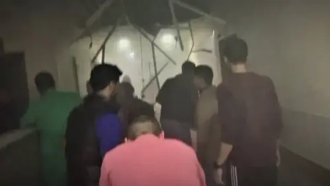 A screengrab from footage taken at Nasser hospital shows people, including in medical scrubs, appearing to run through a corridor