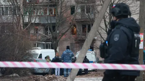 Getty Images Emergency services specialists work by a damaged apartment block after an alleged drone attack reported by local media, in Saint Petersburg