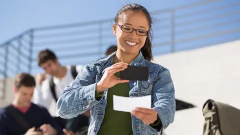 Getty Images A woman takes a picture of a cheque