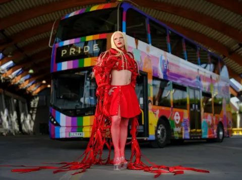 TfL Bimini Bon-Boulash in front of Pride-coloured London bus